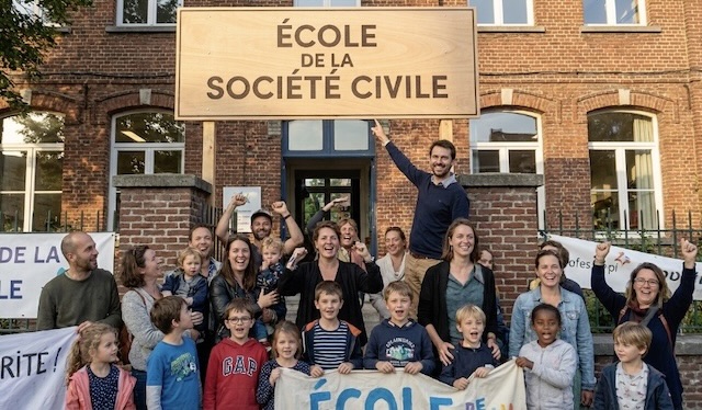 Une photo d'enseignants, de parents et d'enfants devant leur école, qui est une École de la Société Civile -Cette image est générée par IA